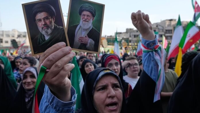 Una mujer iraní sostiene en su mano las imágenes del ayatollah Mojtaba Khamenei y de su padre, Ali Khamenei